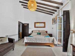 A bedroom with a bed, a wooden headboard, a hanging light fixture, a door, and a window.