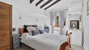Un dormitorio con una cama de madera, una mesita de noche, un aparador y una ventana con cortinas.