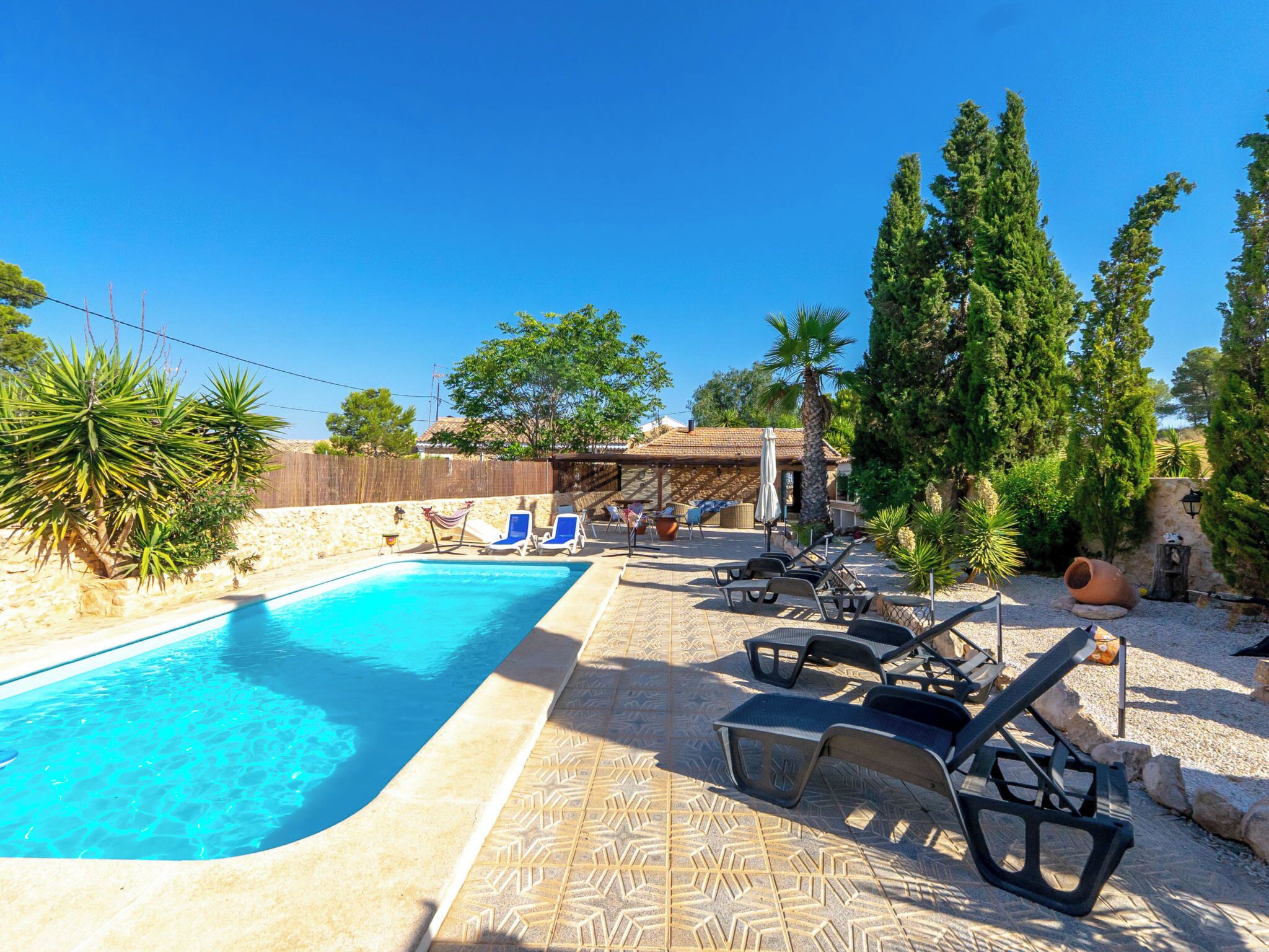 Une piscine avec des chaises longues et une pergola.