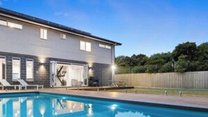 En modern byggnad med en swimmingpool, utomhusmöbler och en trappa som leder upp till en övre våning.