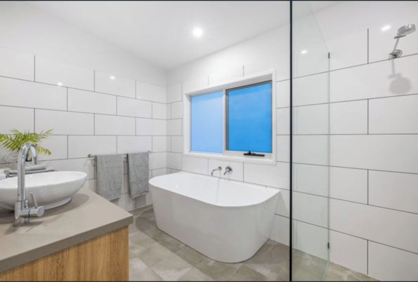 A modern bathroom with a freestanding bathtub, two sinks, and a window.
