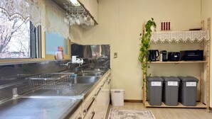 A kitchen with stainless steel appliances, a sink, and a window with a view of cherry blossoms. - The Nest Furano (Furano)