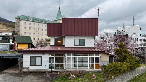 A two-story building with a flat roof, large windows, and a visible chimney. - The Nest Furano (Furano)