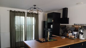 A modern kitchen with a wooden countertop, black cabinets, a built-in oven, and a hanging pot rack.
