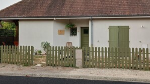 A single-story building with a sloped roof, a wooden fence, and a small porch with a bench.