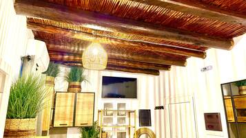 Una habitación con techo de madera, televisor y varios muebles, incluyendo una estantería y un armario.