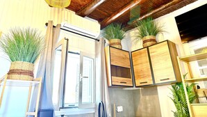 A kitchen with wooden cabinets, a hanging light fixture, and potted plants. - Naousaki Premium Studios 1 - Heart of Naousa, Paros (Naousa)