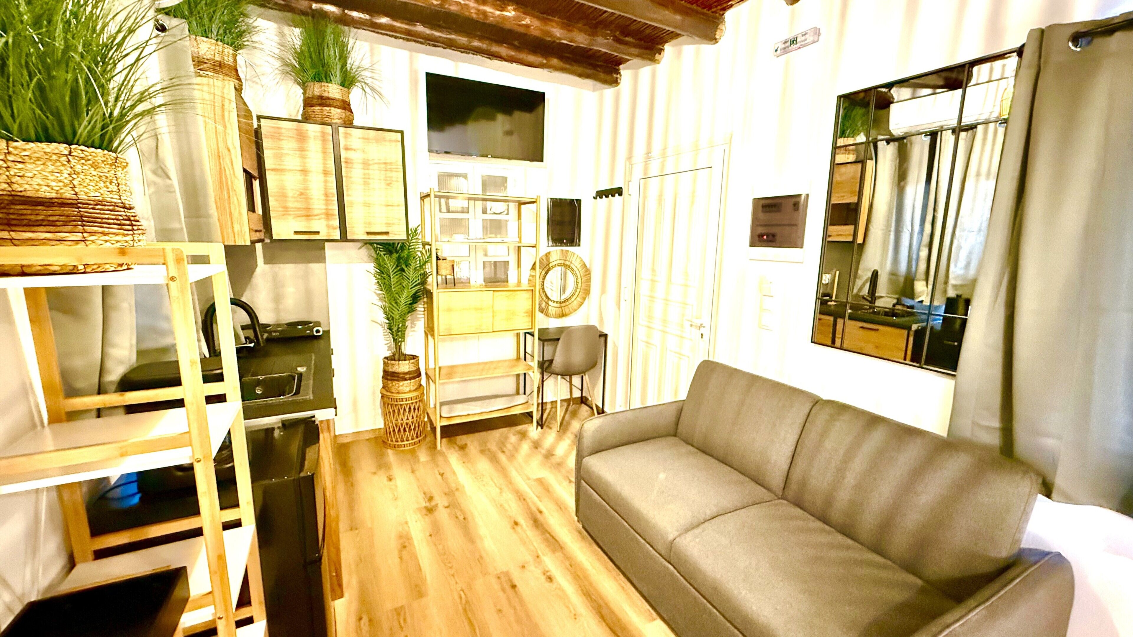 A compact living space with a sofa, a dining table, and kitchen appliances.