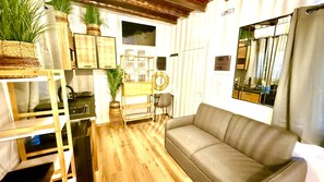 Un espai habitable compacte amb sofà, taula de dinar i electrodomèstics de cuina.