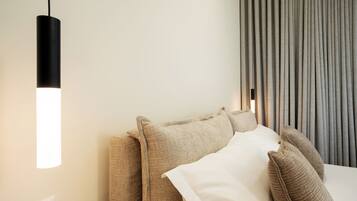 A modern hotel room with a sofa, a bedside table, and a lamp.