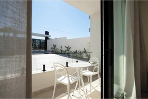 A balcony with a white table and chairs, a view of a building, and a glass railing. - Luxury Villa with swimming pool, jacuzzi,breathtaking views. (Rrashbull)