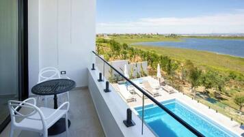 Un balcon avec une piscine, des chaises blanches et une vue sur un lac.