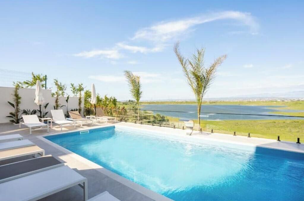 A swimming pool with lounge chairs and a view of a lake.