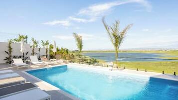 A swimming pool with lounge chairs and a view of a lake.