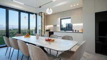 A modern kitchen with a large island, a dining area with a table and chairs, and a view of the outdoors.