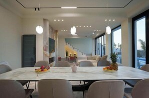 A modern dining area with a marble table, chairs, and a fruit centerpiece.