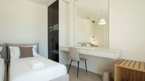 Ein modernes Hotelzimmer mit Bett, Schreibtisch, Stuhl und Spiegel.