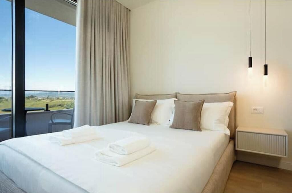 Une chambre d’hôtel avec un grand lit, une vue sur l’extérieur et une fenêtre avec des rideaux.