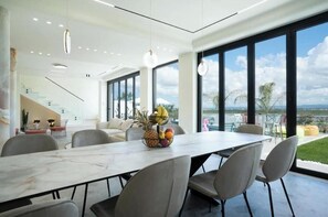 A modern dining area with a marble table, grey chairs, and a fruit bowl. - Luxury Villa with swimming pool, jacuzzi,breathtaking views. (Rrashbull)