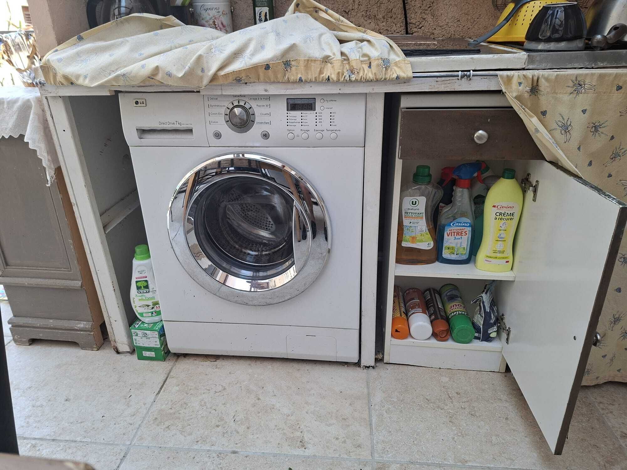 Een kleine wasmachine met bedieningspaneel en een plank met schoonmaakmiddelen.