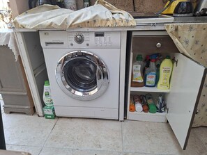 A compact washing machine with a control panel and a shelf with cleaning products. - A peaceful retreat—the perfect starting point for exploring the untamed beauty of Corsica’s valleys. (Moltifao)