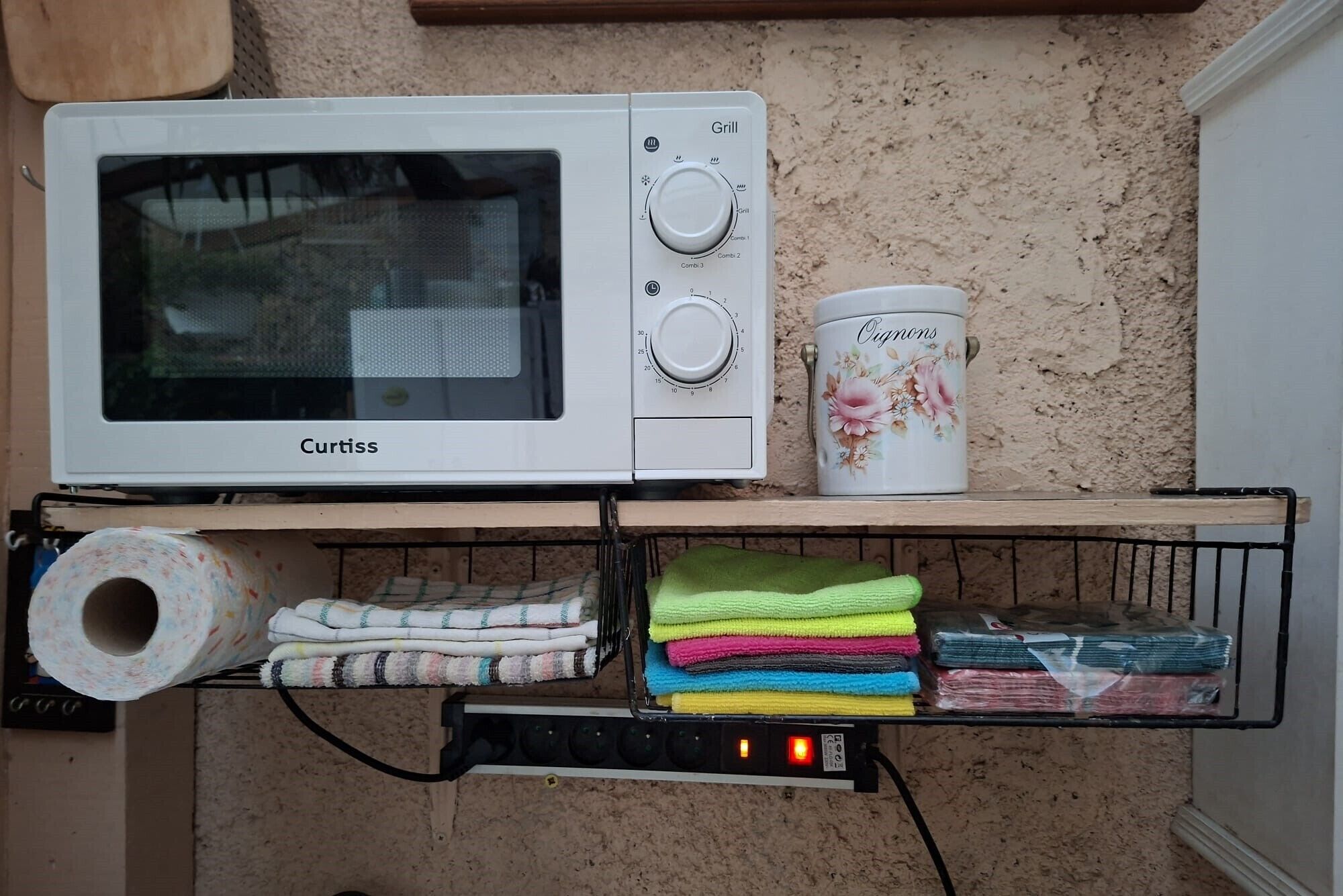 Eine Küche mit Mikrowelle, Toilettenpapierrolle und einem Behälter mit der Aufschrift 'Origamis'.