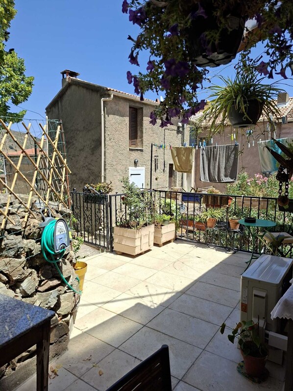 A courtyard with a stone wall, a metal fence, and potted plants. - A haven of peace—the perfect starting point for exploring the untamed beauty of the Corsican valleys. (Moltifao)