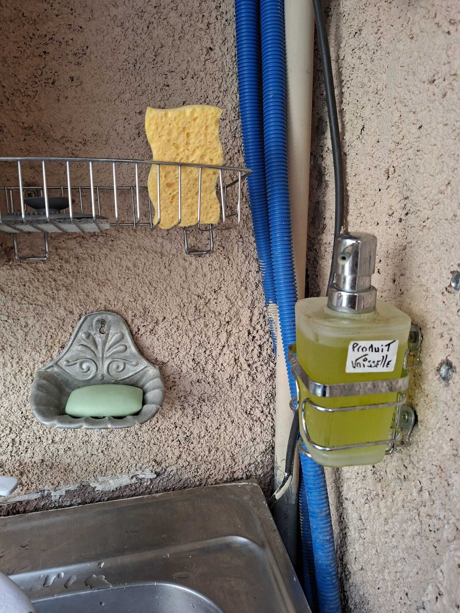 Ein Badezimmer mit Waschbecken, Seifenschale, Schwamm und einer Flasche Pro Juventiselle Parfum.