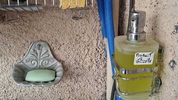 Ein Badezimmer mit Waschbecken, Seifenschale, Schwamm und einer Flasche Pro Juventiselle Parfum.