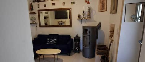 Una sala de estar con sofá, mesa, televisor y chimenea.