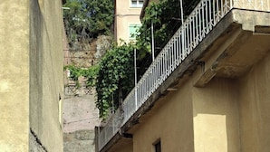 Unes escales estretes que condueixen a un edifici amb barana metàl·lica i un cartell amb la inscripció 'AEROSININE'.