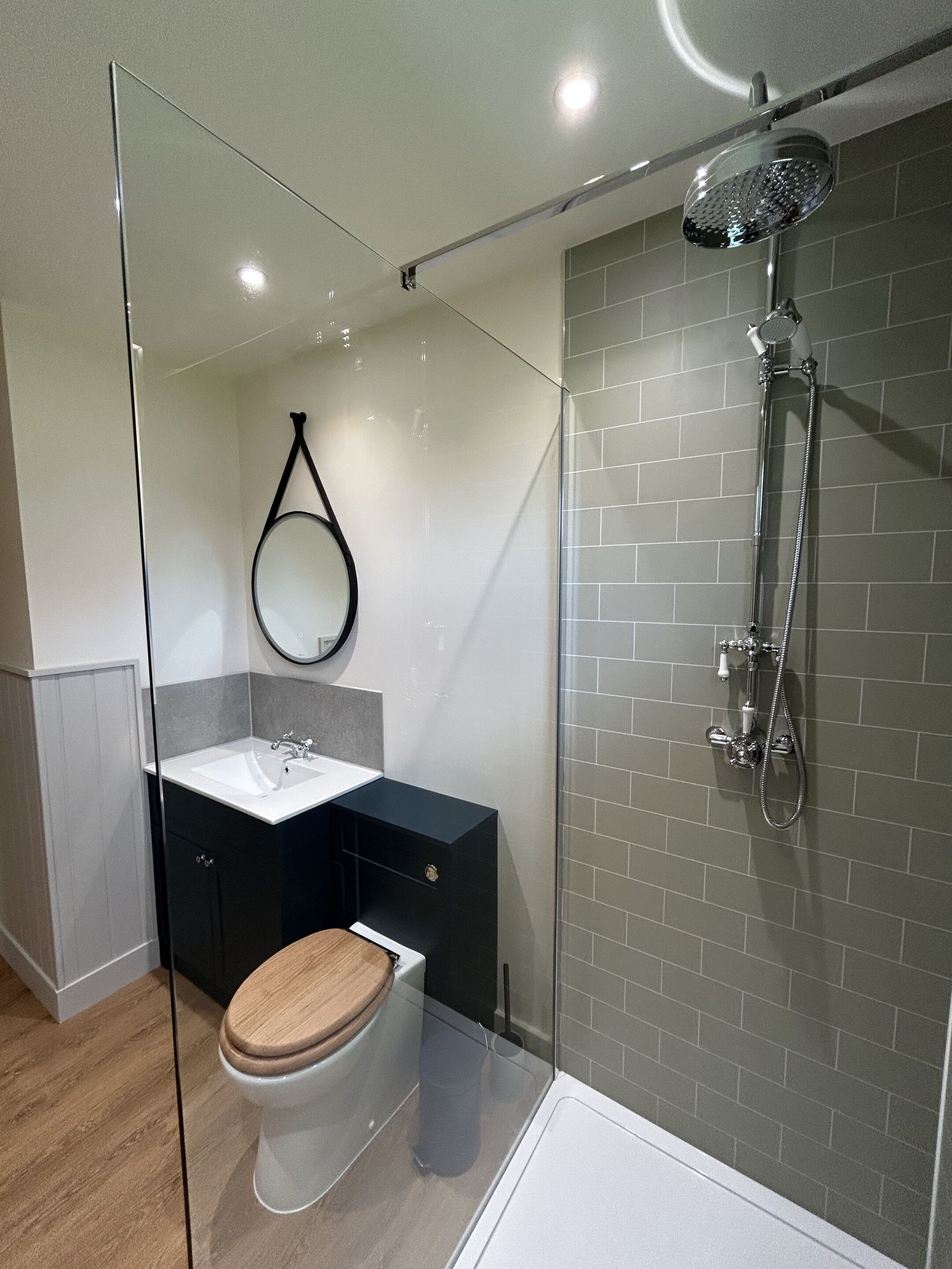 A modern bathroom with a glass shower enclosure, a toilet, and a sink with a mirror.