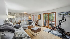 Ett vardagsrum med en soffa, ett soffbord, en lampa och en motionscykel.