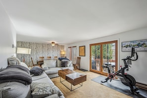 Ein Wohnzimmer mit Sofa, Couchtisch, Lampe und Crosstrainer.