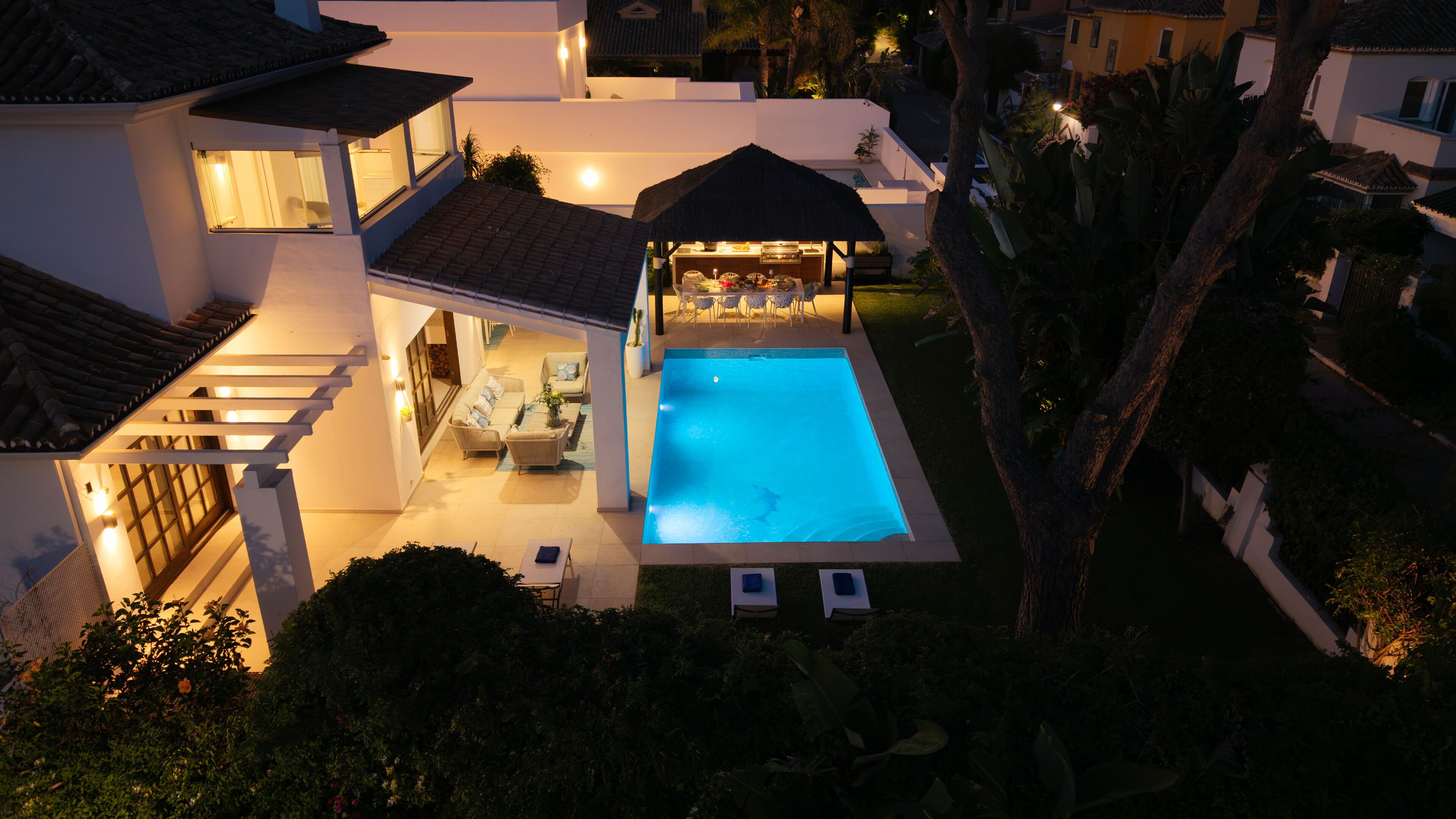 A residential property with a swimming pool, outdoor seating, and a covered patio area.