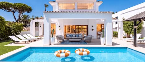 Una casa moderna con piscina, area salotto esterna e patio.