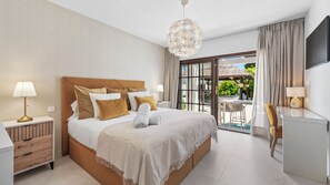 A hotel room with a large bed, a desk, a chair, a TV, and a balcony with a table and chairs. - Villa Marblanc by Vacation Marbella (Estepona)