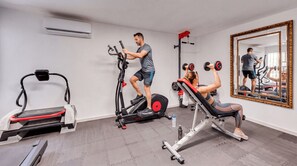 Un gimnasio con equipo de ejercicio, una cinta de correr y un espejo.