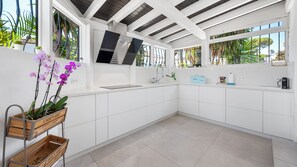 A modern kitchen with white cabinetry, a built-in oven, and a window overlooking a garden. - Villa Marblanc by Vacation Marbella (Estepona)