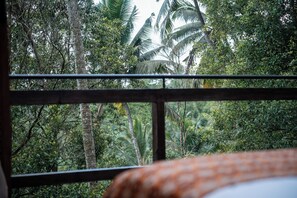 A room with a view of dense tropical foliage through a window with a metal frame. - Oak House Sidemen (Sidemen)