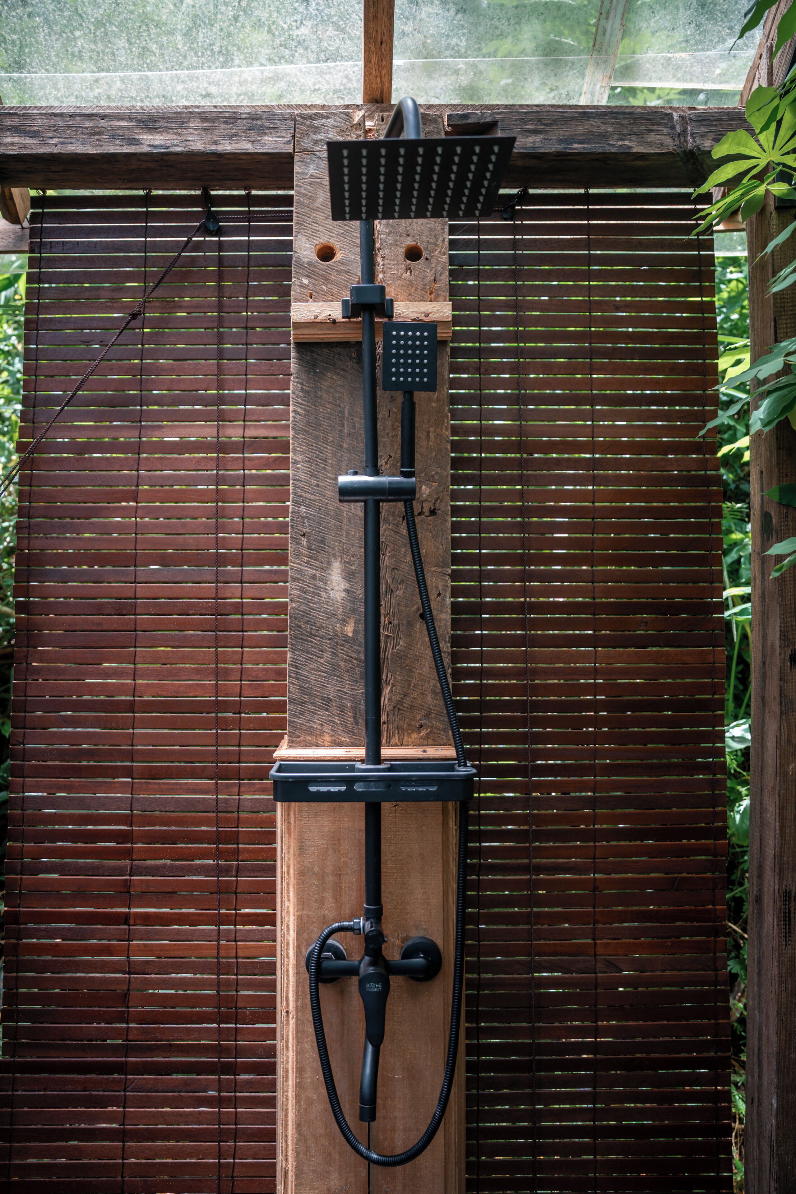 Een verticale tuin met een houten constructie, een metalen waterpartij en een houten hek.