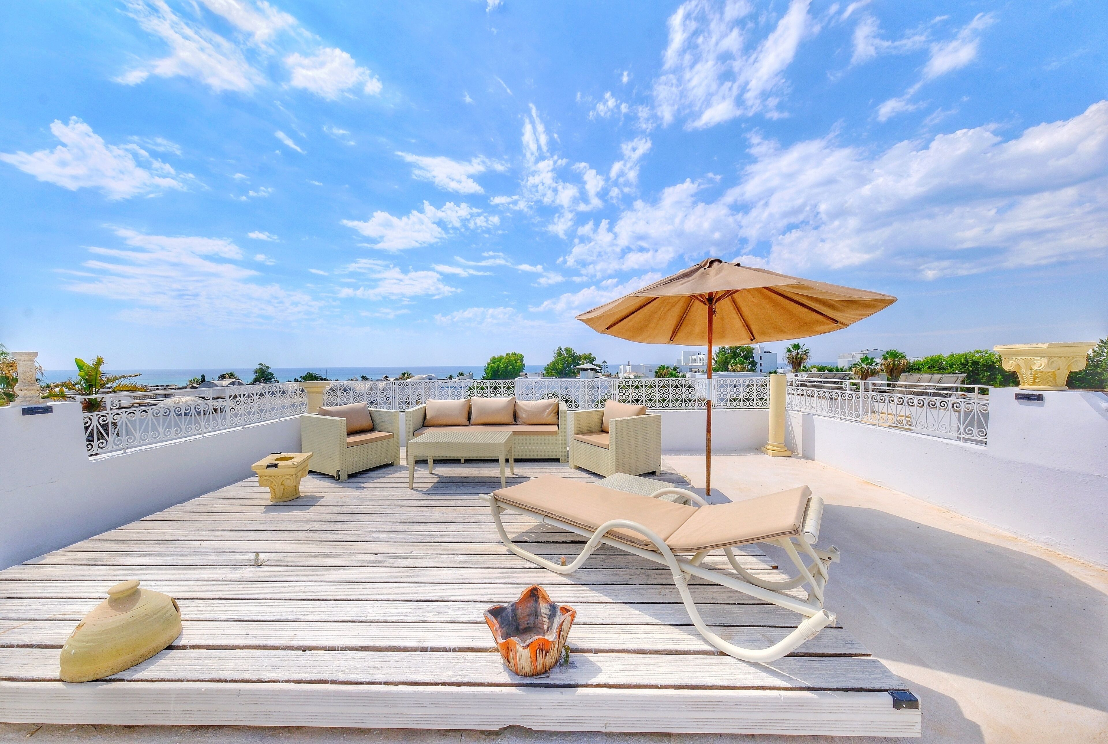A rooftop terrace with outdoor furniture, a decorative bowl, and a view of the sea.