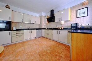 A kitchen with white cabinets, a black oven, and a tiled backsplash. - Villa in Marrakech - La Badira Neighborhood - Hammamet, with a pool 300 meters from the beach (hammamet)