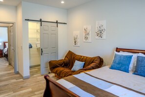 A bedroom with a bed, a brown leather sofa, and a door leading to a bathroom. - Fall Escape Special: 15% Discount Ends Nov 30! Must book by Oct 18 (Pagosa Springs)