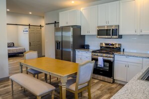 A modern kitchen with white cabinets, stainless steel appliances, a dining table with chairs, and a bench. - Fall Escape Special: 15% Discount Ends Nov 30! Must book by Oct 18 (Pagosa Springs)