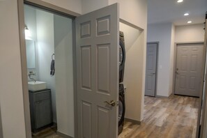 A hallway with a door leading to a bathroom, a washing machine, and a door to another room. - Fall Escape Special: 15% Discount Ends Nov 30! Must book by Oct 18 (Pagosa Springs)