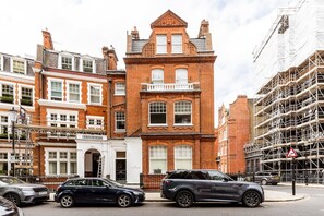 A historic building with a brick facade, large windows, and a prominent entrance. - Charming Two-Bed in South Kensington (London)