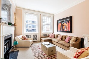 Ein Wohnzimmer mit Kamin, einer Sofagarnitur, einem Couchtisch und einem Bild an der Wand.