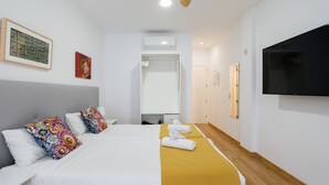 A hotel room with a bed, a television, a ceiling fan, and a door leading to a bathroom. - Beachfront Apartment in Las Palmas by Las Canteras (Las Palmas de Gran Canaria)