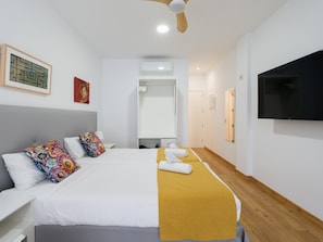 A hotel room with a bed, a television, a ceiling fan, and a door leading to a bathroom. - Beachfront Apartment in Las Palmas by Las Canteras (Las Palmas de Gran Canaria)